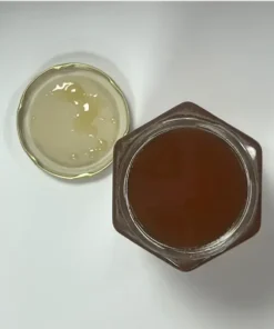 Pot de miel de thym ouvert vu du dessus avec son couvercle, sur fond blanc.
